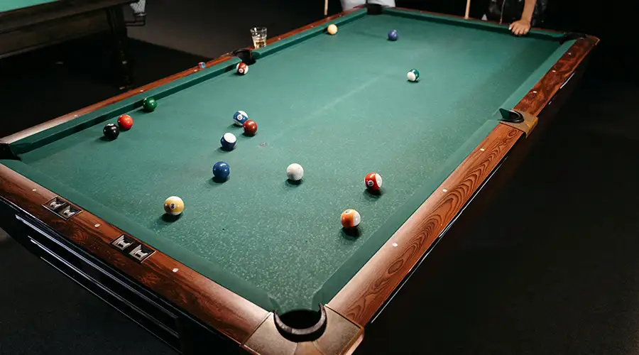 Technician precisely leveling slate during professional pool table installation